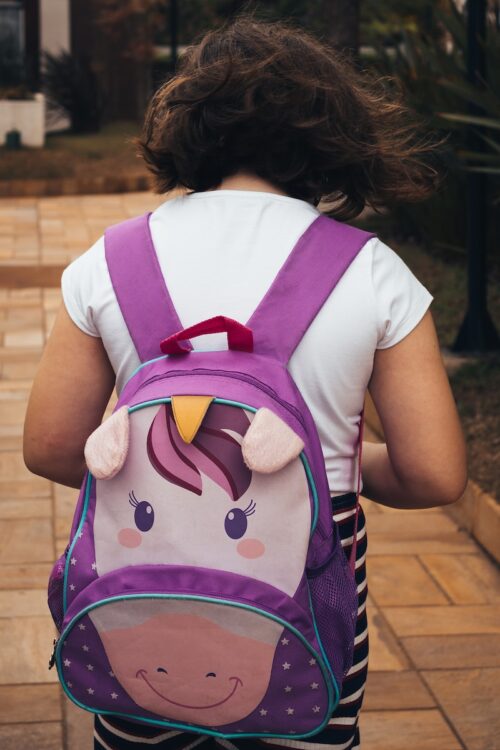 girl in white shirt carrying purple backpack
